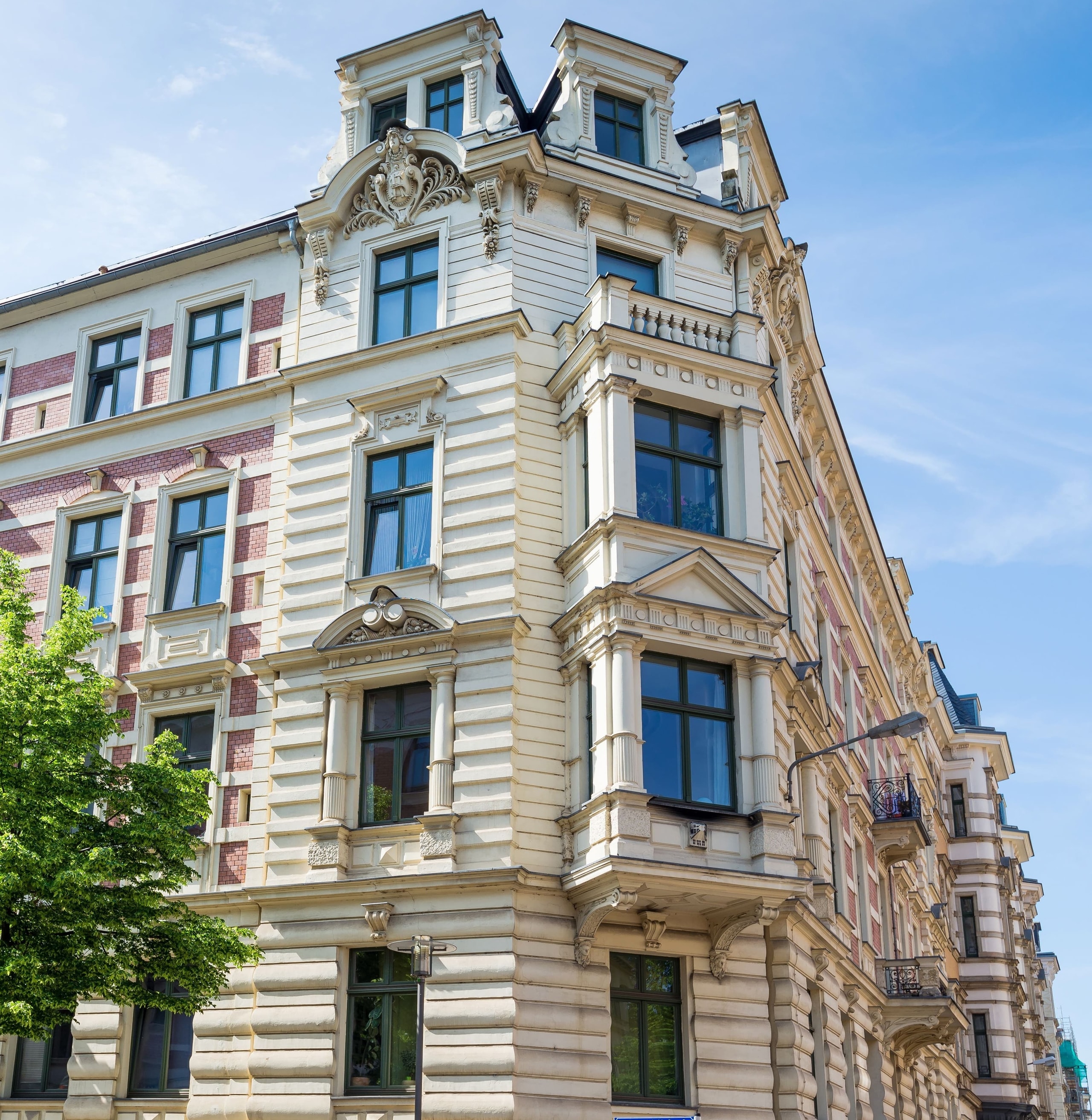 Sanierte Gründerzeit-Altbaufassade mit Stuck und Erker vor blauem Himmel
