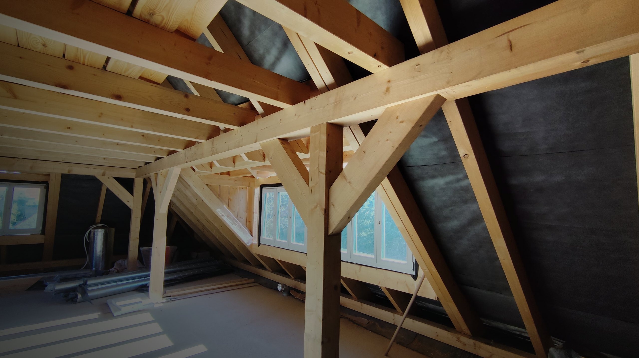 Offener Dachstuhl mit Holzsparren und Dachfenstern während des Dachausbaus im Rohbau