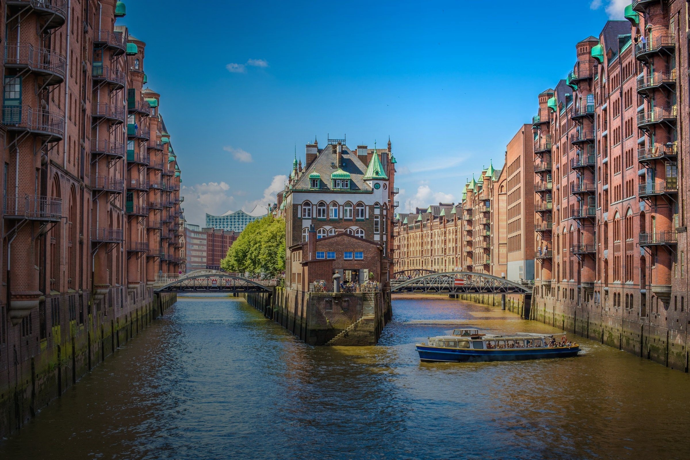 Speicherstadt Hamburg mit Fleet, historischen Backsteinbauten und Ausflugsboot bei Sonnenschein